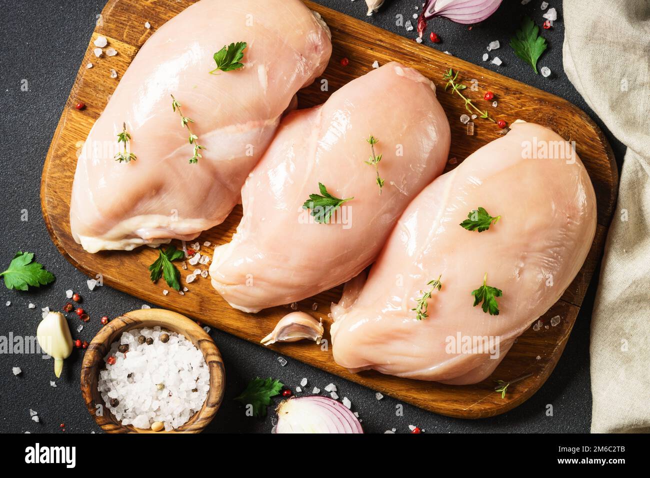 Hähnchenbrust mit Gewürzen auf Holzbrett. Stockfoto