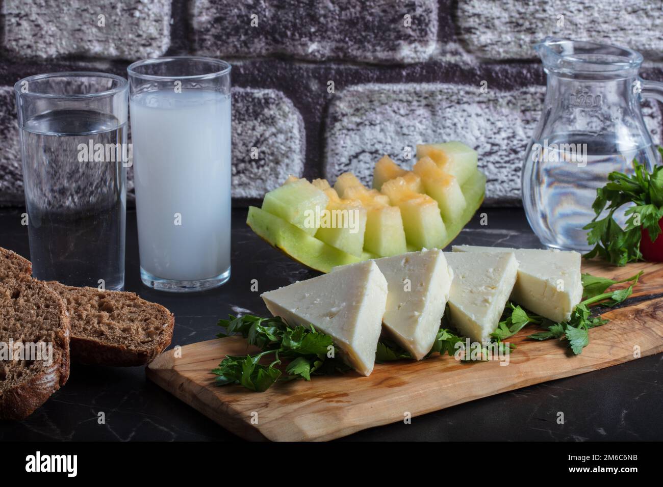 Türkisches Raki mit Wasser auf dem Tisch mit Melonenscheiben und Vorspeise, traditioneller türkischer Alkohol, bekannt als Raki, Chill mit Freunden im Restaurant, Abendessen Stockfoto