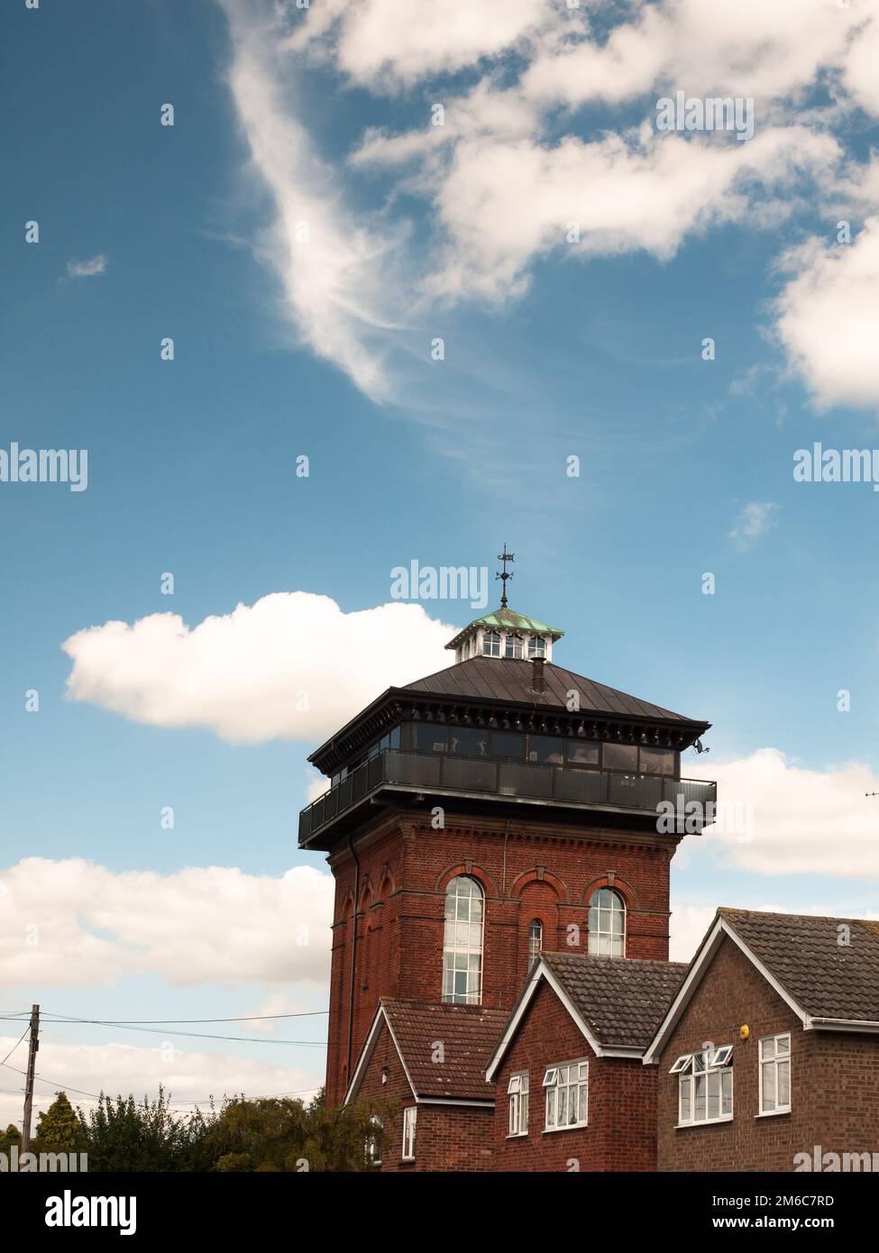 Ein Wasserturm wandelte ein Haus mit blauem Himmel und Wolken ein Stockfoto