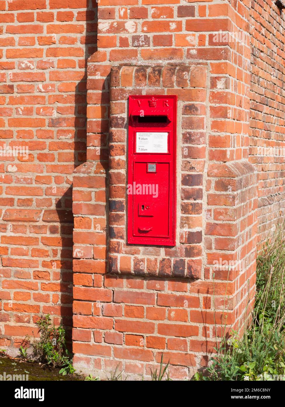 Nahaufnahme des roten königlichen Briefkastens in Backsteinmauern Stockfoto