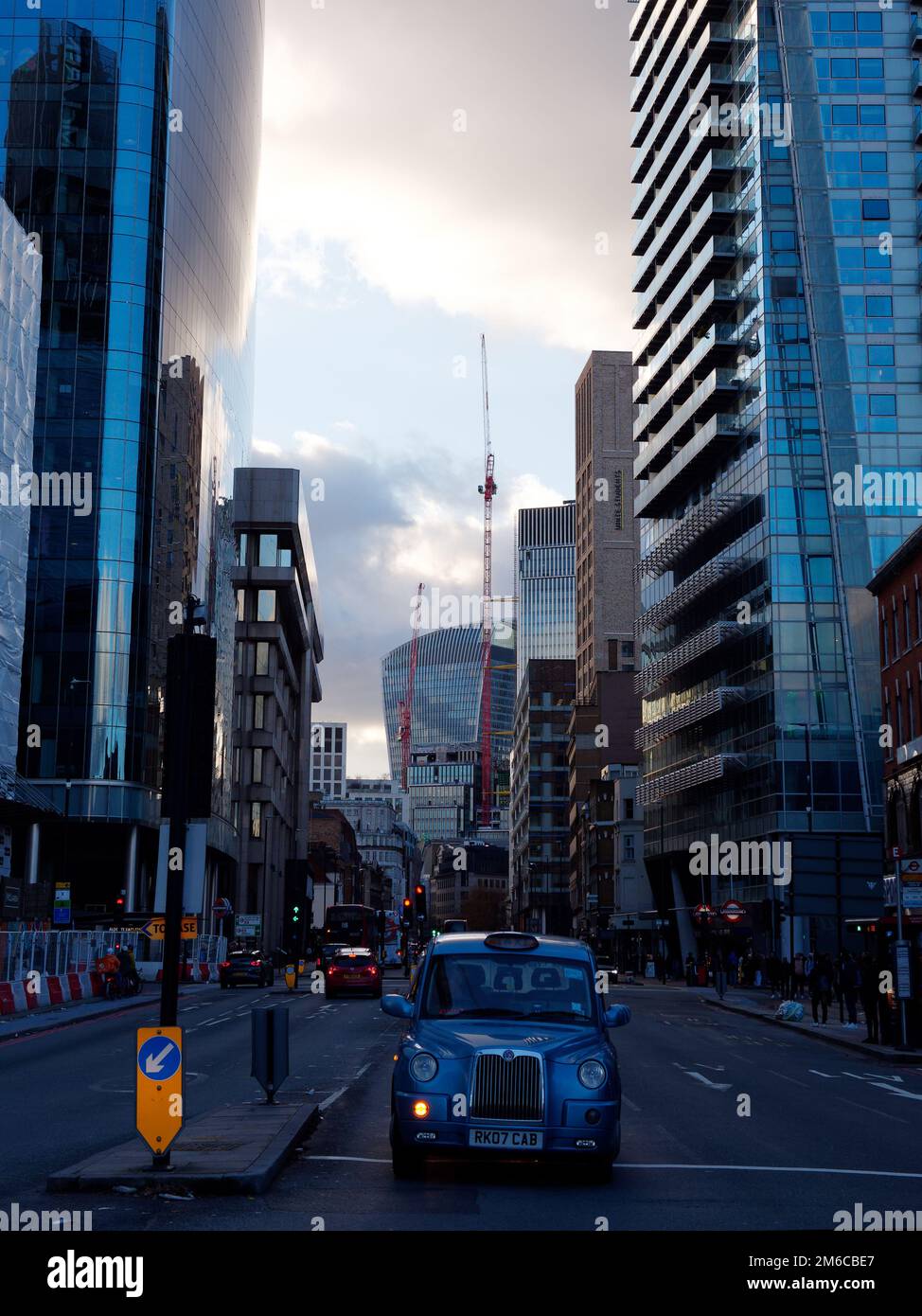 Das blaue Taxi wartet an einer Kreuzung in London mit einem dramatischen Abendhimmel und dem Walkie Talkie Wolkenkratzer. England. Stockfoto