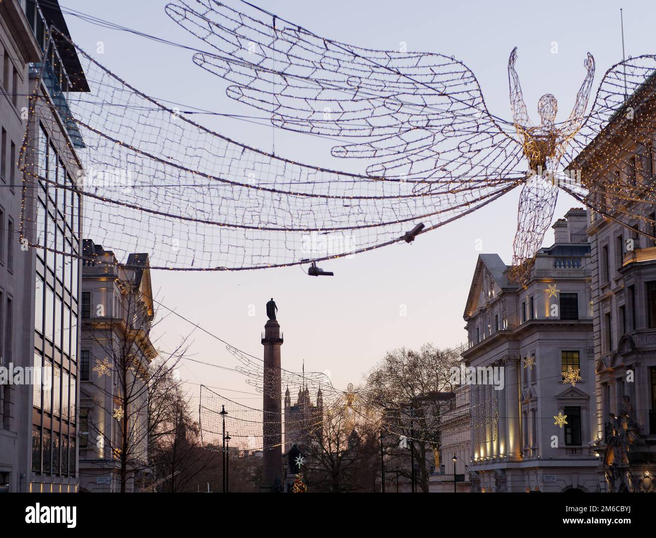 Weihnachtsgeister hängen über der Regent Street St. James. Waterloo Place und Houses of Parliament hinter London, England. Stockfoto