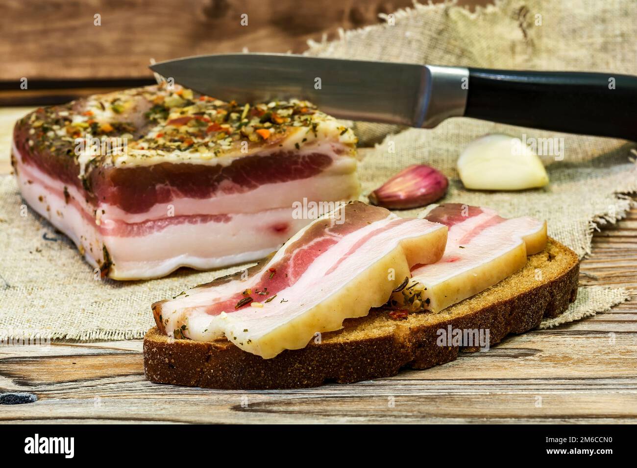 Zwei Scheiben gesalzenen Speck auf schwarzem Brot liegen auf dem Tisch Stockfoto