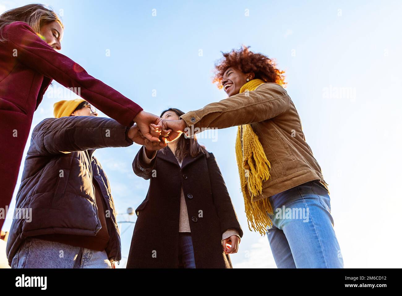 Multirassische Gruppe von Freunden, die sich im Freien zusammenstoßen und Einheit zeigen Stockfoto