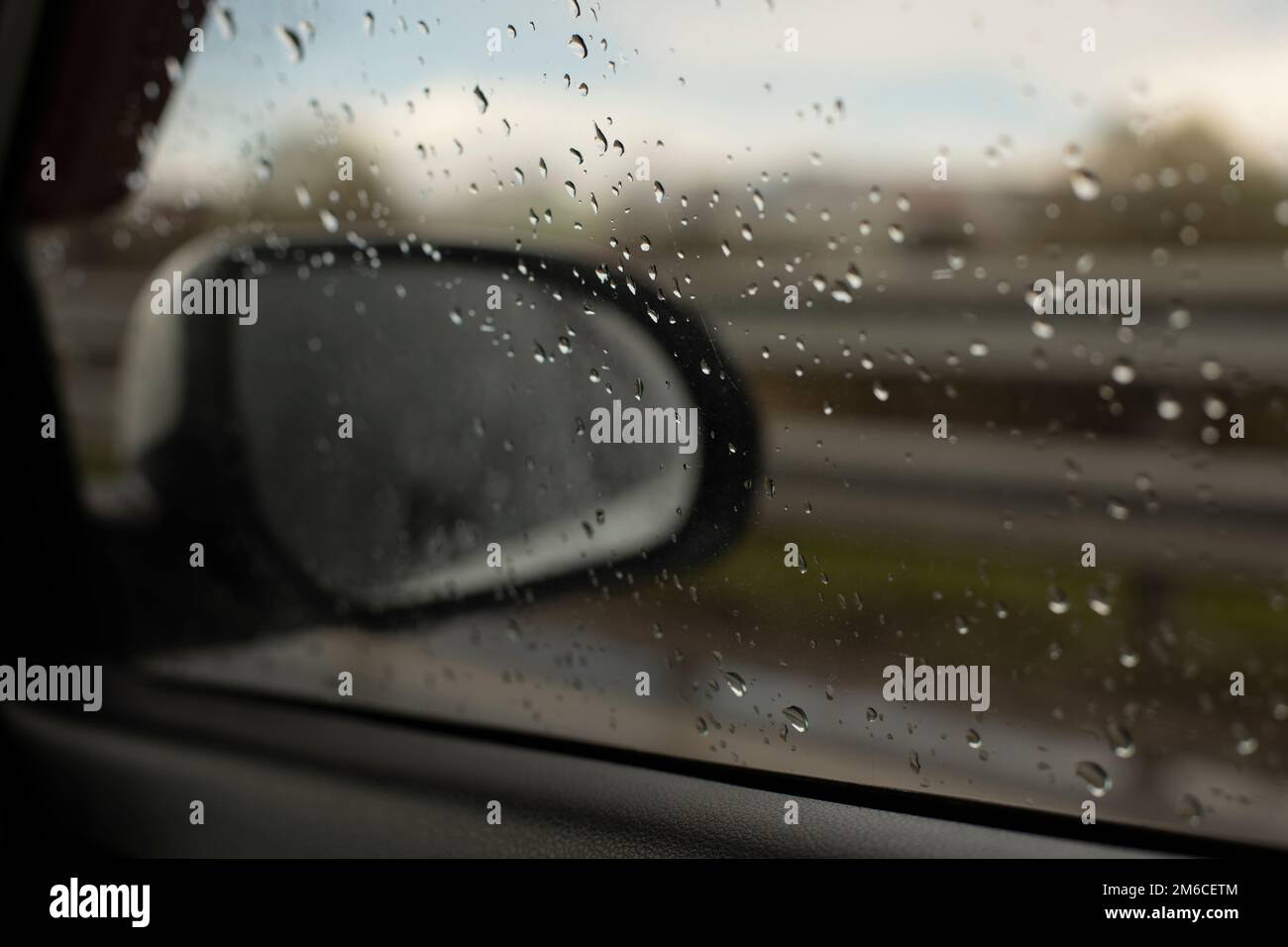 Rückspiegel eines Autos hinter nassem Glas. Stockfoto
