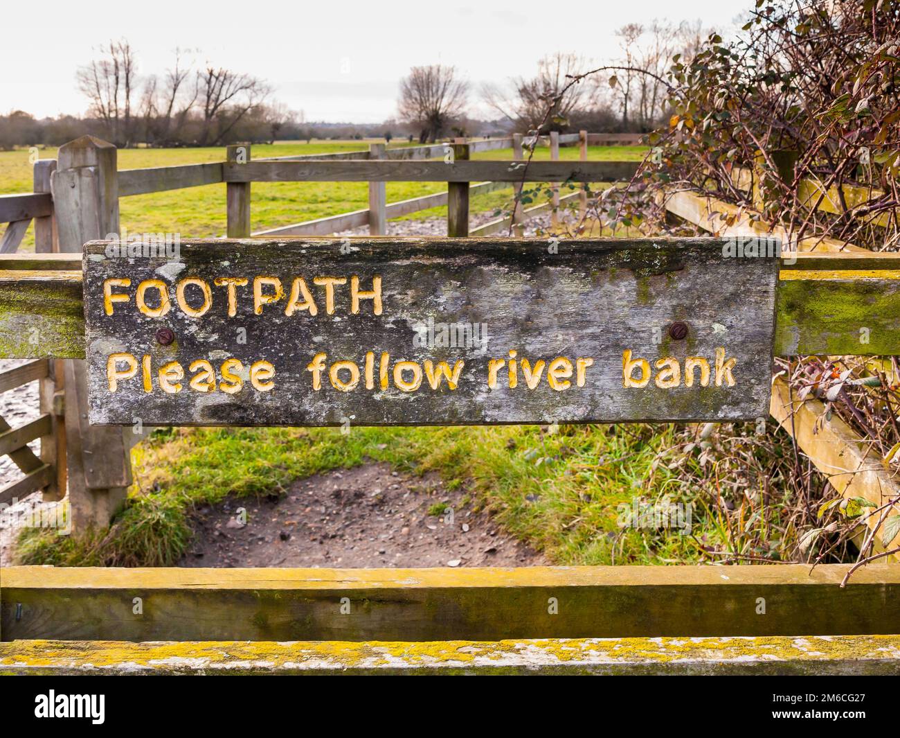 Fußweg folgen Sie bitte dem gelben, eingravierten Holzzaun-Schild am Flussufer aus nächster Nähe Stockfoto