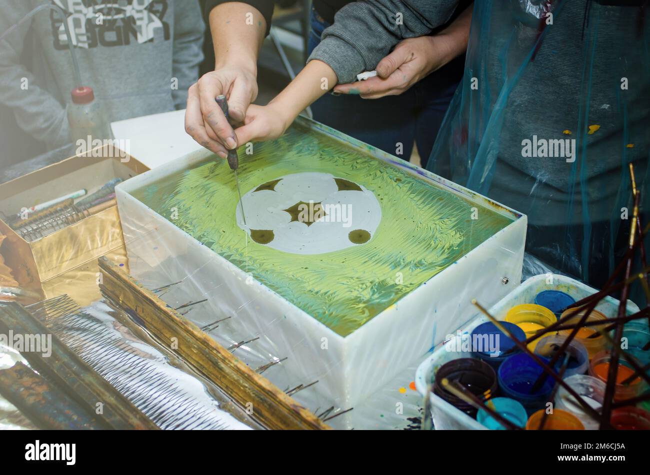 Der Meister lehrt die Technik des ebru. Die Hände schließen sich Stockfoto