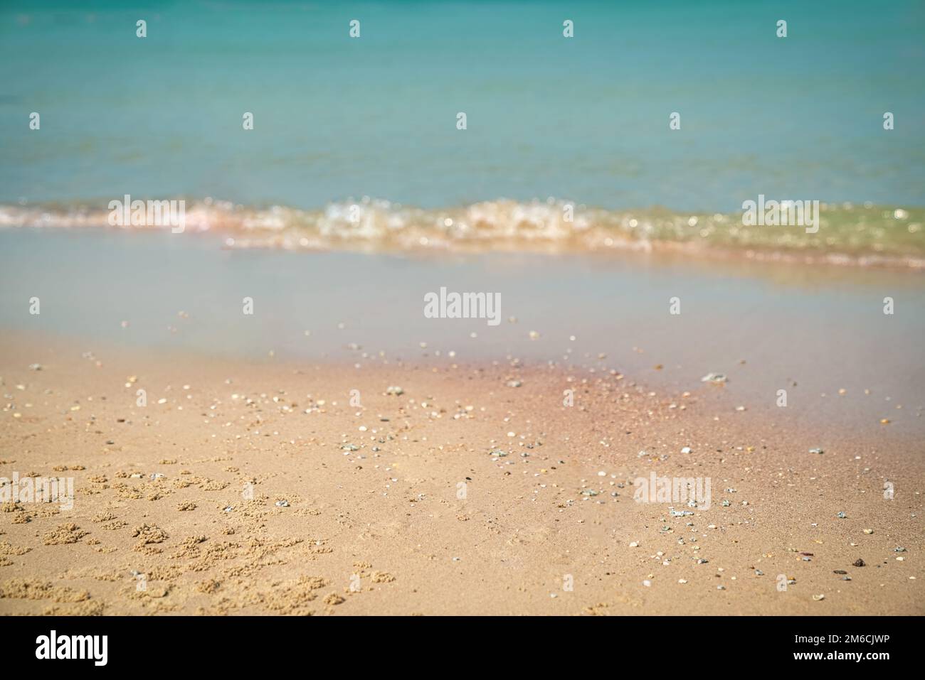 Sand mit verschwommenen Wellen im Hintergrund. Sandstrand, Sommerurlaub. Speicherplatz kopieren. Stockfoto