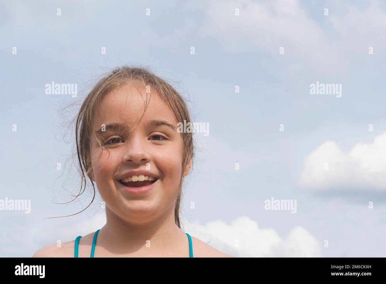 Ein kleines Mädchen auf dem Meer vor blauem Himmel und Wolken Stockfoto