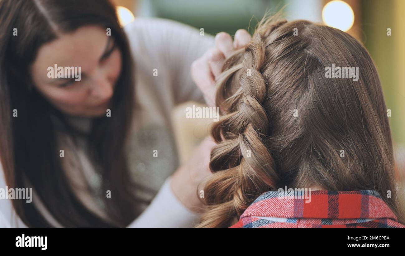 Die Make-up-Künstlerin macht einen Zopf für das Model. Stockfoto