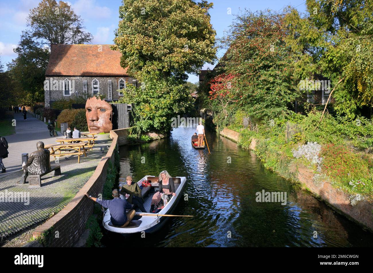 Kahnboote auf dem Great Stour River oder River Stour, Canterbury, Kent, England, Großbritannien. Schott-Masken-Skulptur vor dem Blackfriars-Kloster. Stockfoto