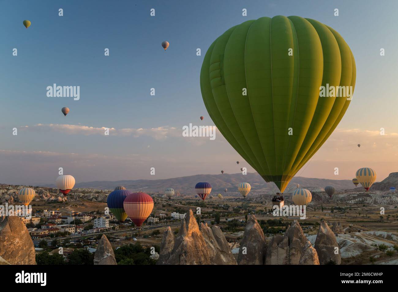 Heißluftballons fliegen bei Sonnenaufgang über Felsformationen in Kappadokien, Türkei Stockfoto