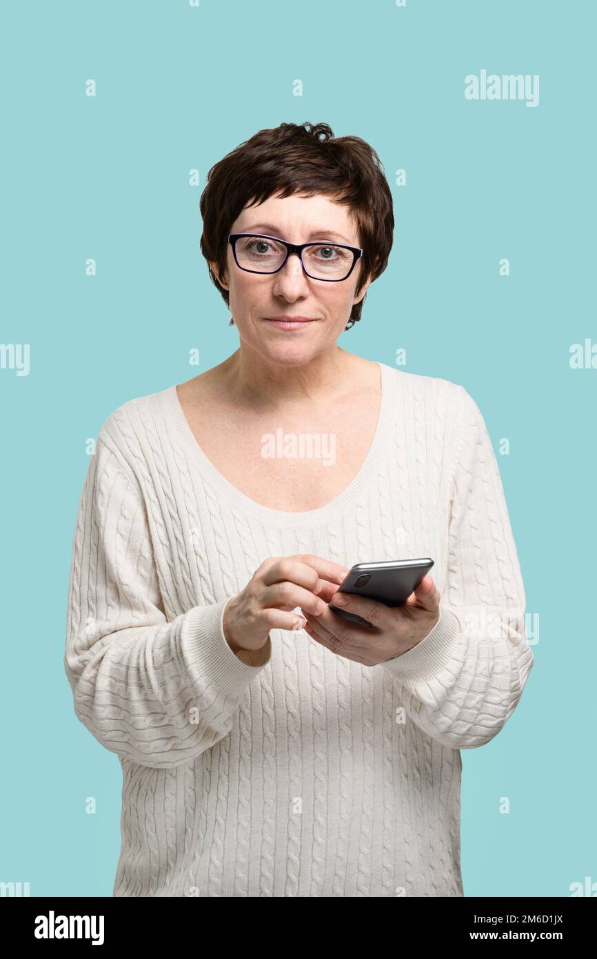 Erwachsene Frau mit Smartphone in der Hand, die in die Kamera schaut Stockfoto