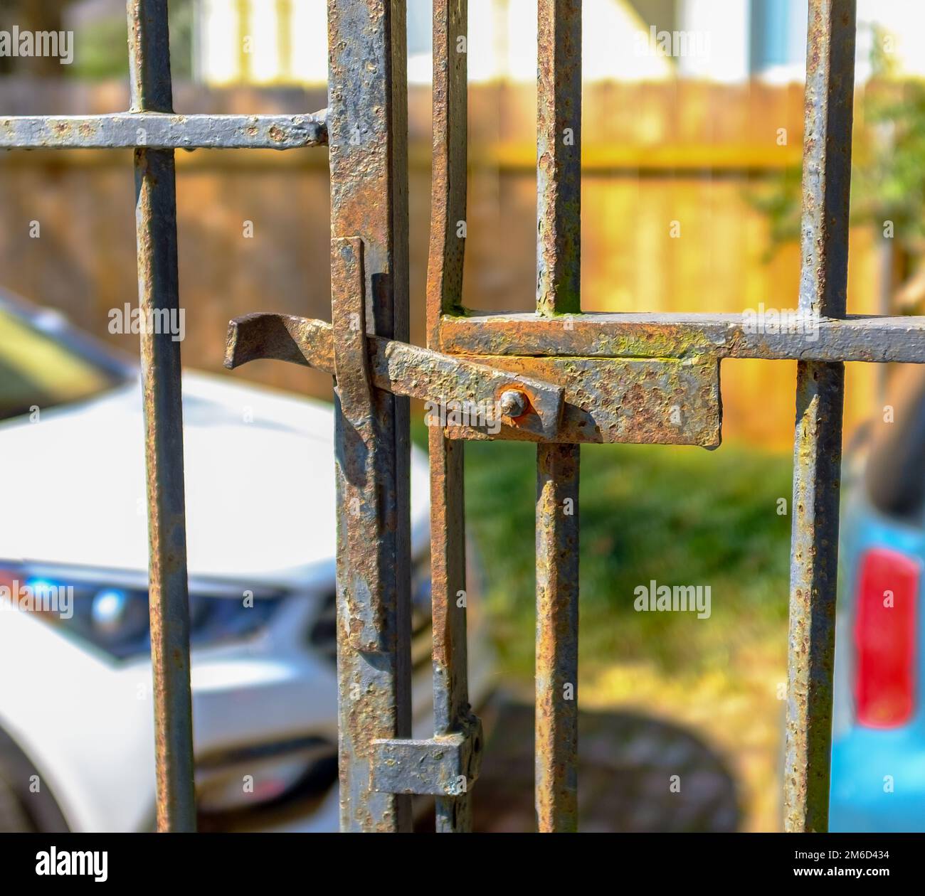 Am 31. Oktober 2020 in New Orleans, Louisiana, USA, befindet sich das antike, eingerastete Metalltor mit geparkten Autos und Holzzaun im Hintergrund Stockfoto