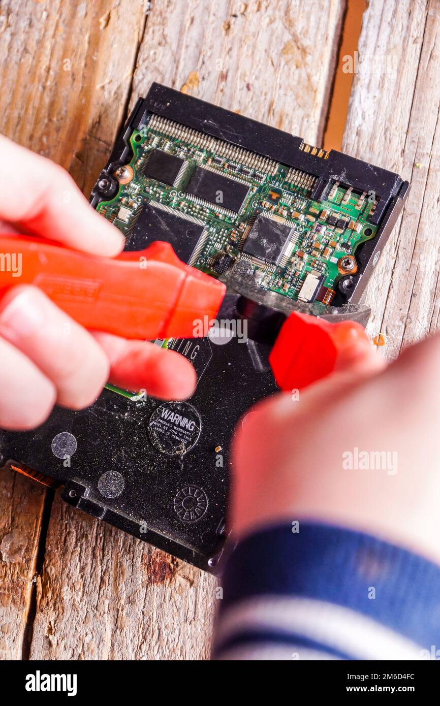 Ein Mann zerbricht einen Computer mit Schlosser. Stockfoto