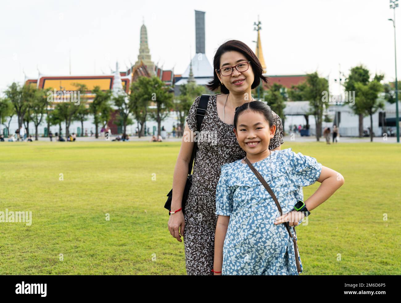 Porträt asiatische Touristenmutter und kleine Tochter in Sanam Luang oder Freifeld und öffentlicher Platz vor Wat Phra Kaew und dem Großen Palast, Bangk Stockfoto
