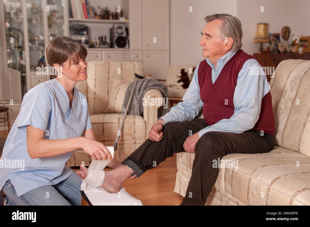 Der Pfleger bindende Fuß des Seniorenmannes Stockfoto