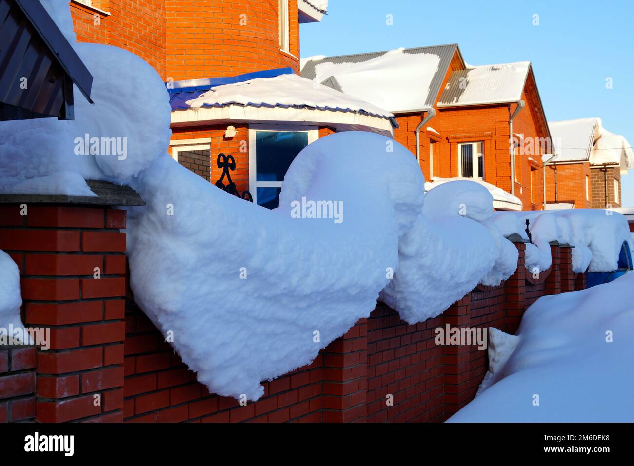 Auf einem Wohnhaus liegt viel Schnee und große Schneeverwehungen. Stockfoto