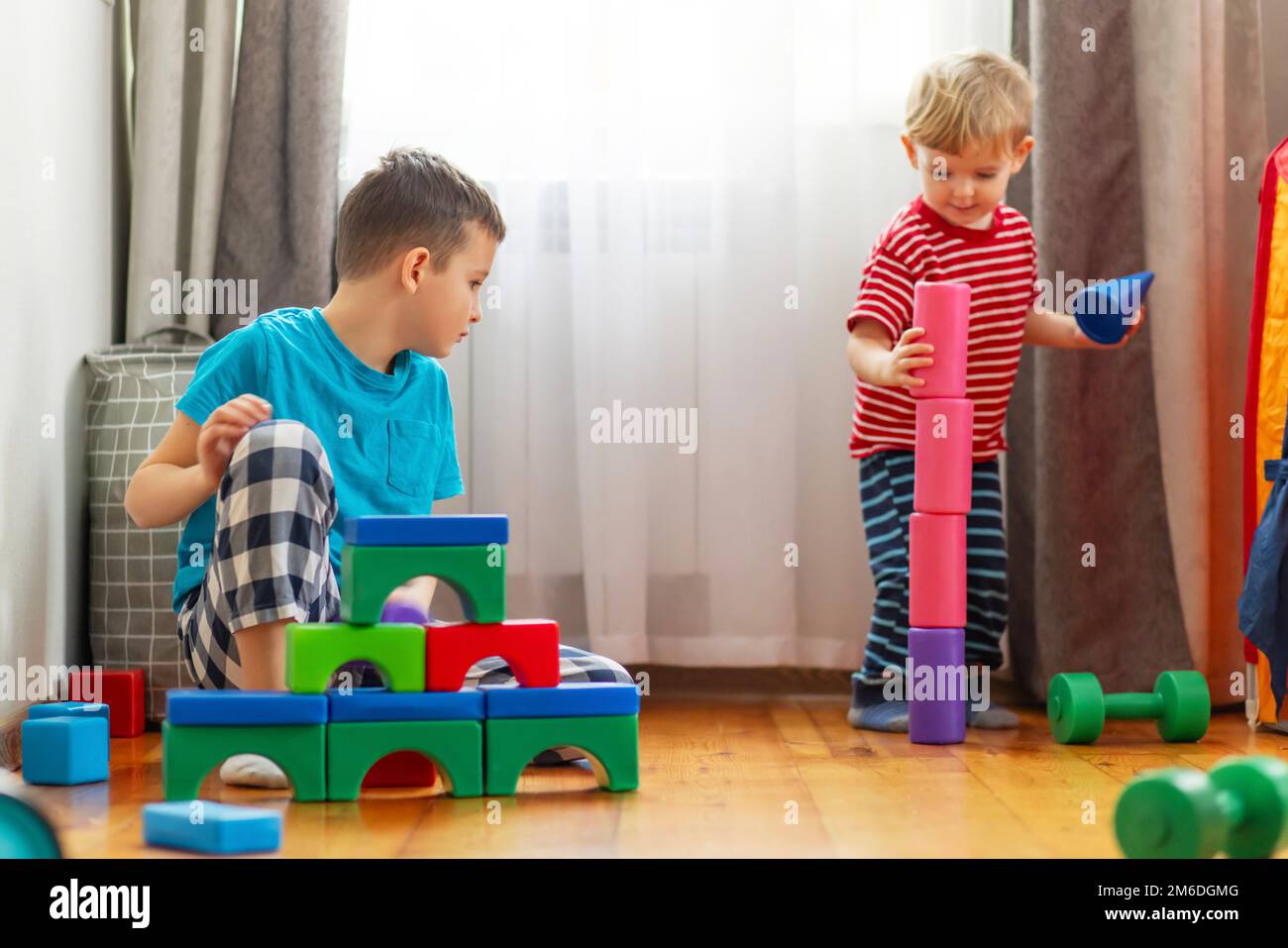 Niedliche kleine Kinder, die mit bunten Plastikspielzeugen oder Bausteinen spielen Stockfoto