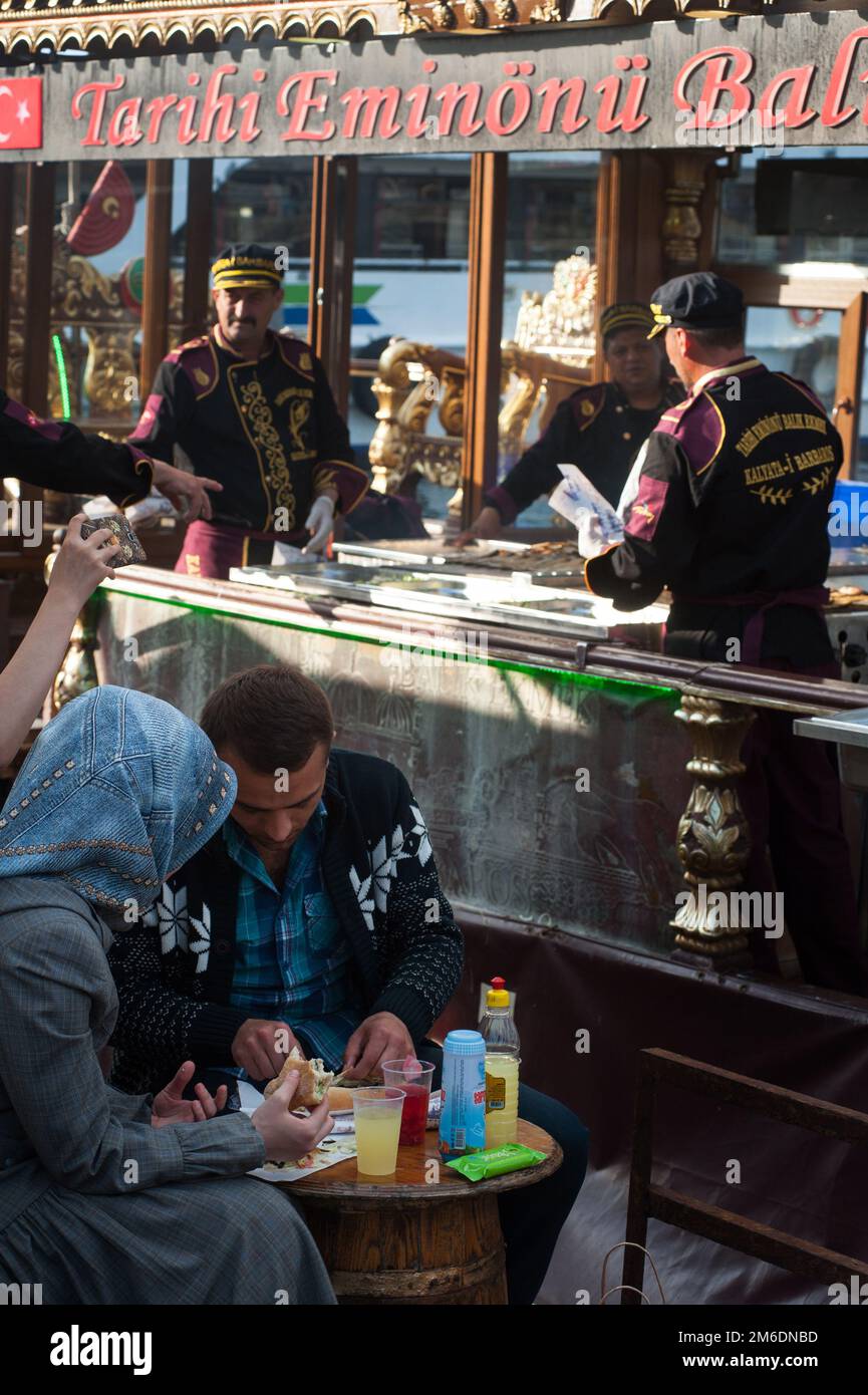 Ein türkisches Paar isst ein Fischsandwich, das berühmte Street Food Balik Ekmek neben dem Goldenen Horn, ich Stockfoto