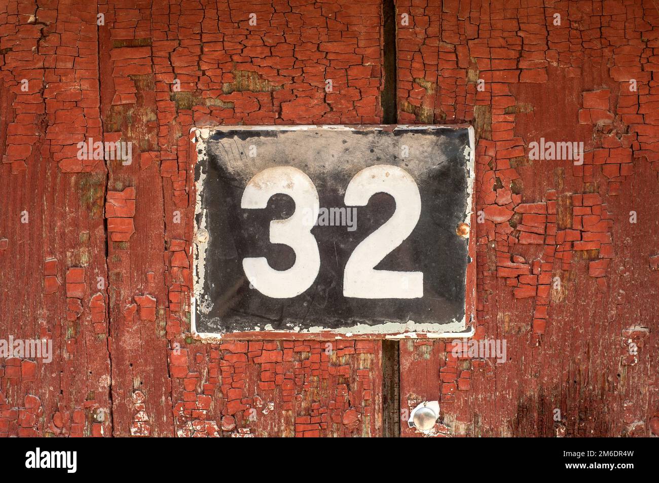 Verwitterte, quadratische Metall-Emaillierte Platte mit der Nummer der Straßenadresse mit der Nummer 32 in der Nähe Stockfoto