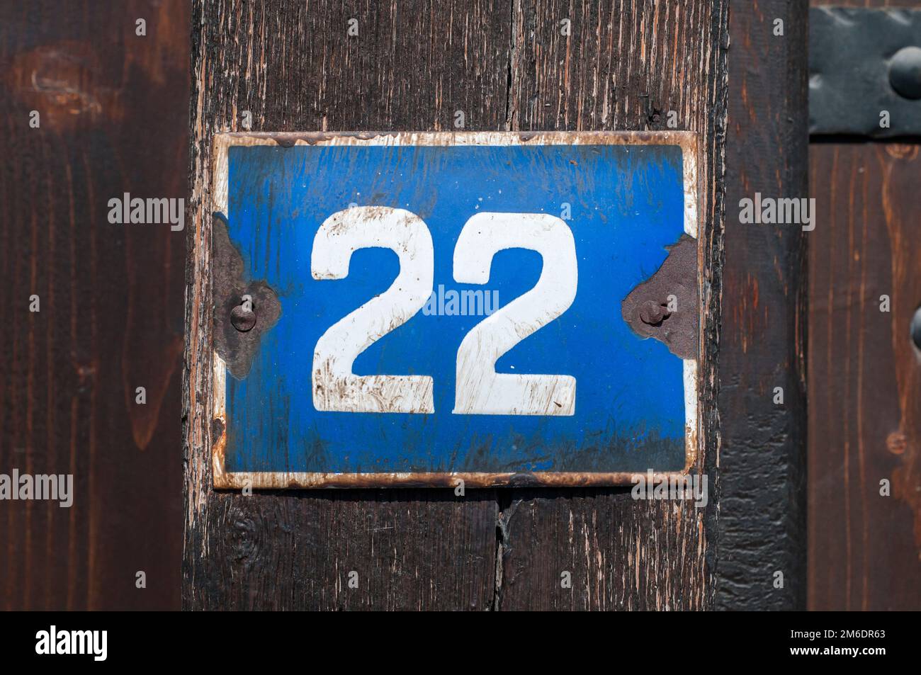 Verwitterte, quadratische Metall-Emaillierte Platte mit der Nummer der Straßenadresse mit der Nummer 22 in der Nähe Stockfoto