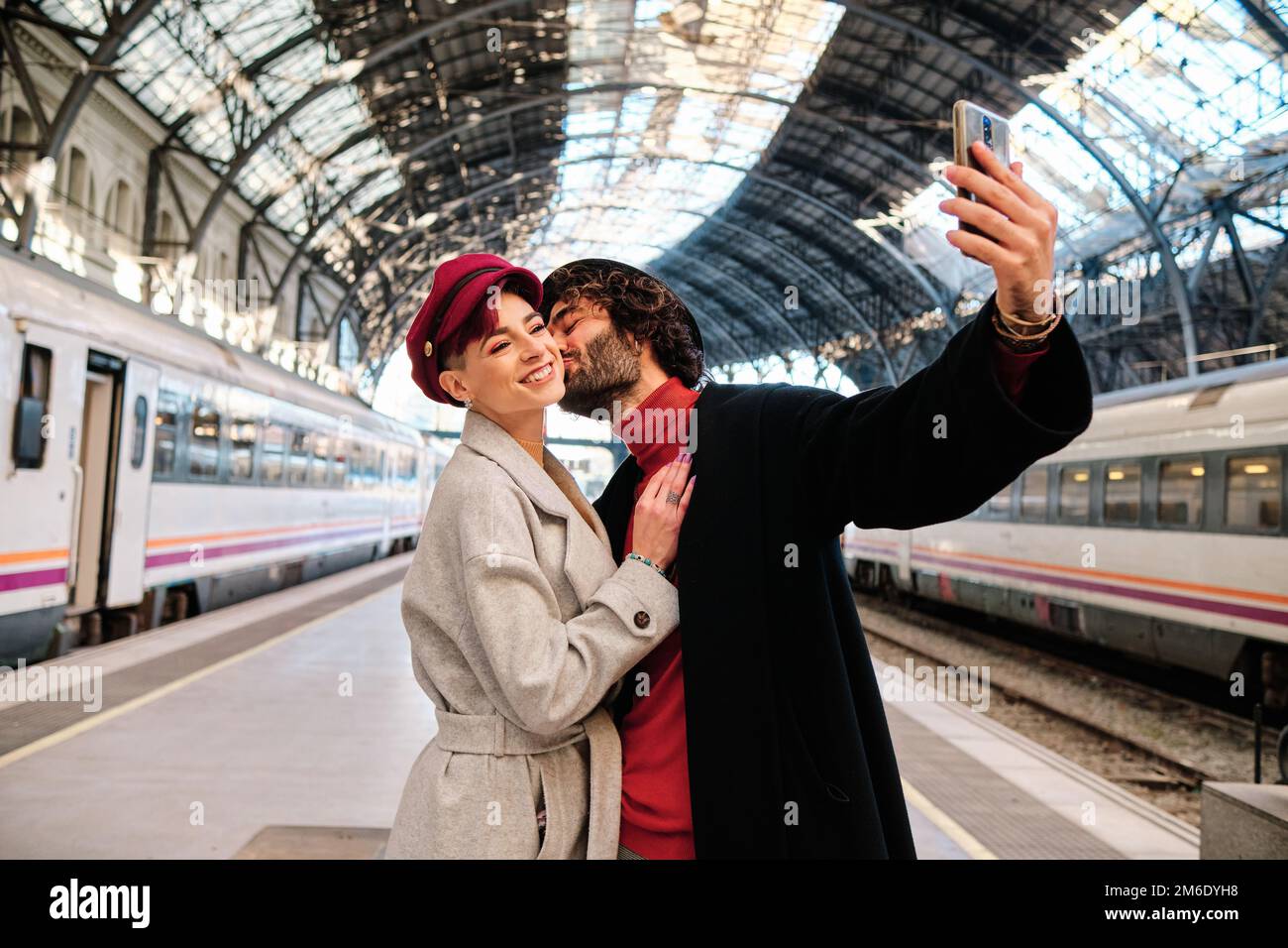 Ein Paar küsst sich, während es ein Selfie in einem Bahnhof macht Stockfoto