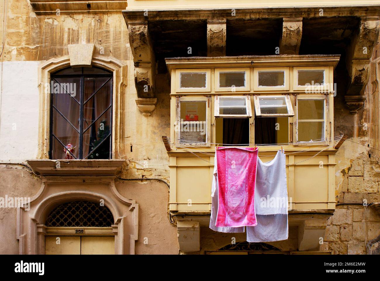 Bunte Kleidung oder Wäsche, die auf einer in Malta fotografierten Schnur getrocknet wird, einer Fassade eines historischen Gebäudes im Hintergrund Stockfoto