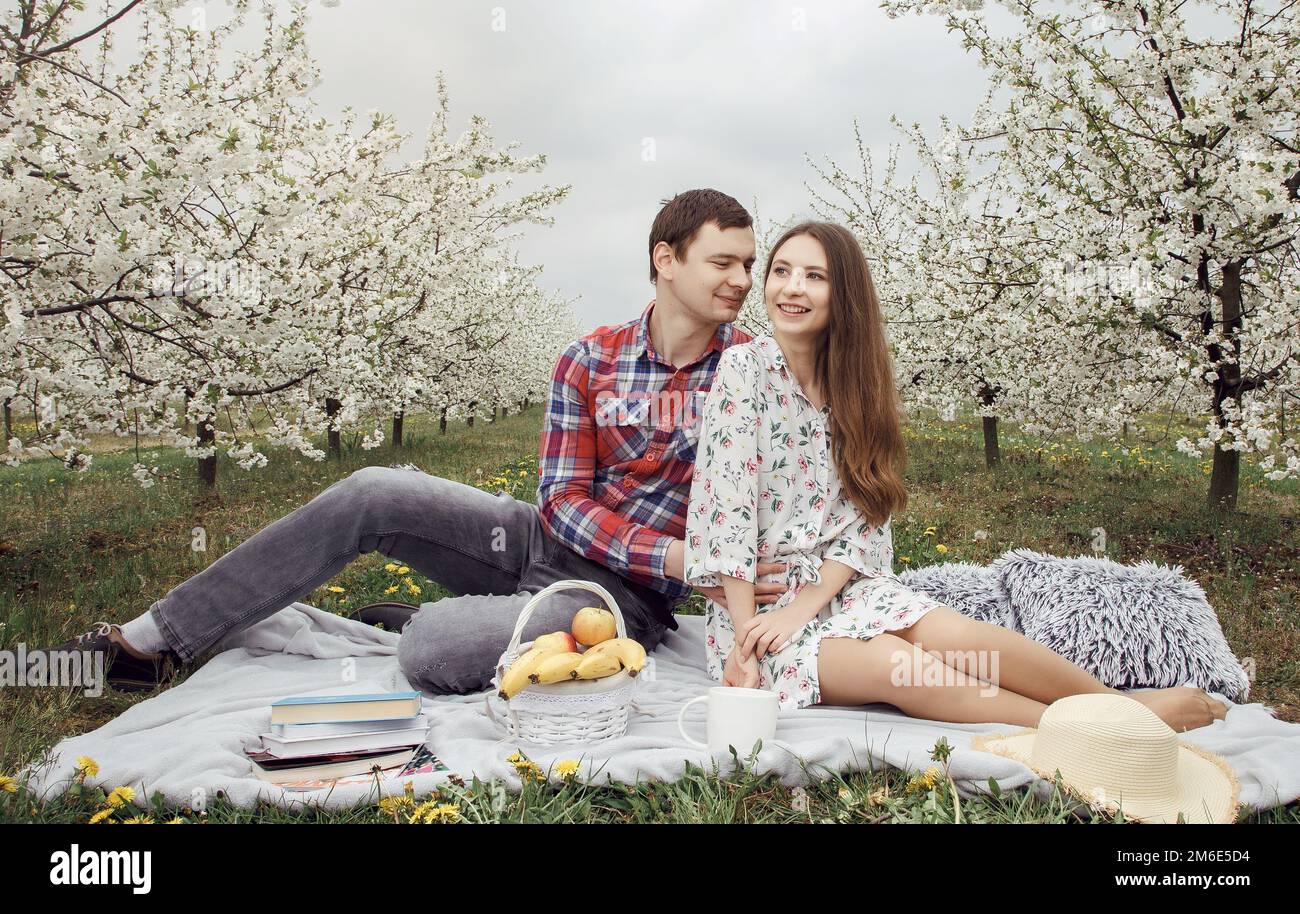 Ein junges Paar, das sich im Garten entspannt. Ein Mädchen mit einem Kerl im Garten. Verliebt auf einem Spaziergang in der Natur. Stockfoto