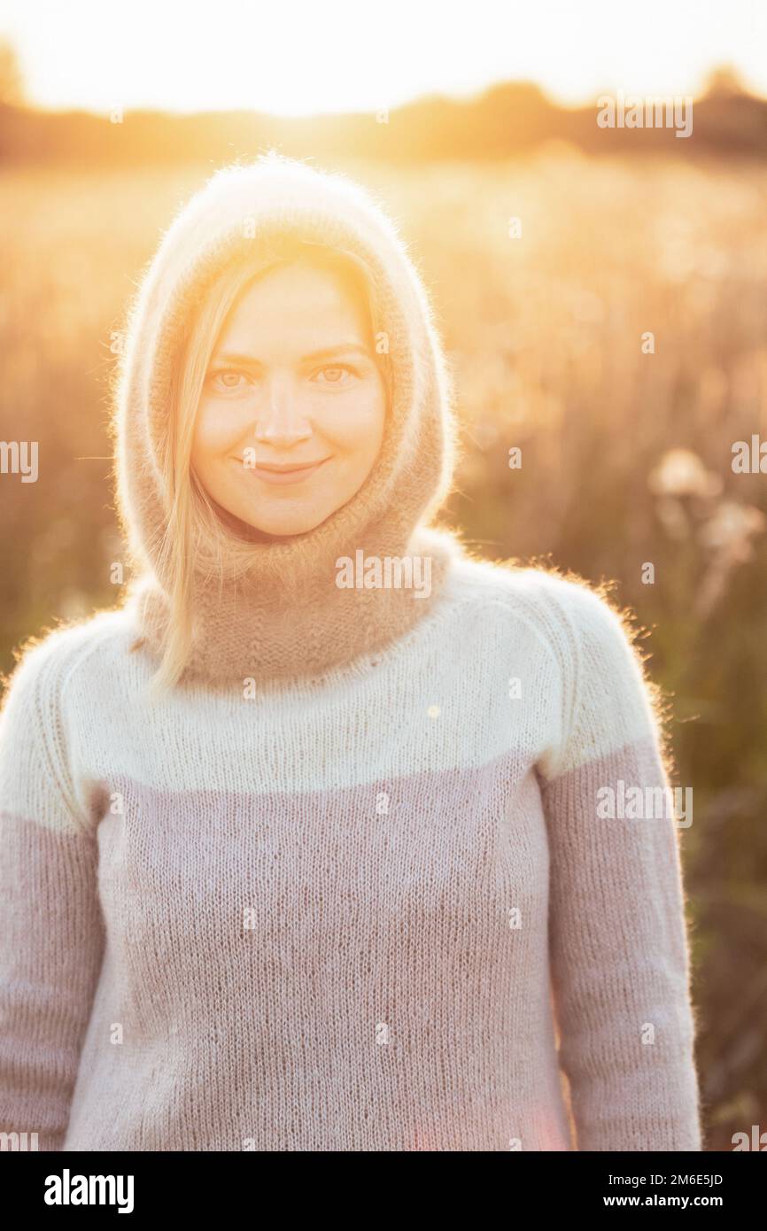 Portrait of Young Pretty Caucasian Happy Girl Woman in Woolen Jacket Bluse und Brown gestrickte Haube posiert im frühen Frühlingswald in Sunny Day. Viel Spaß Stockfoto