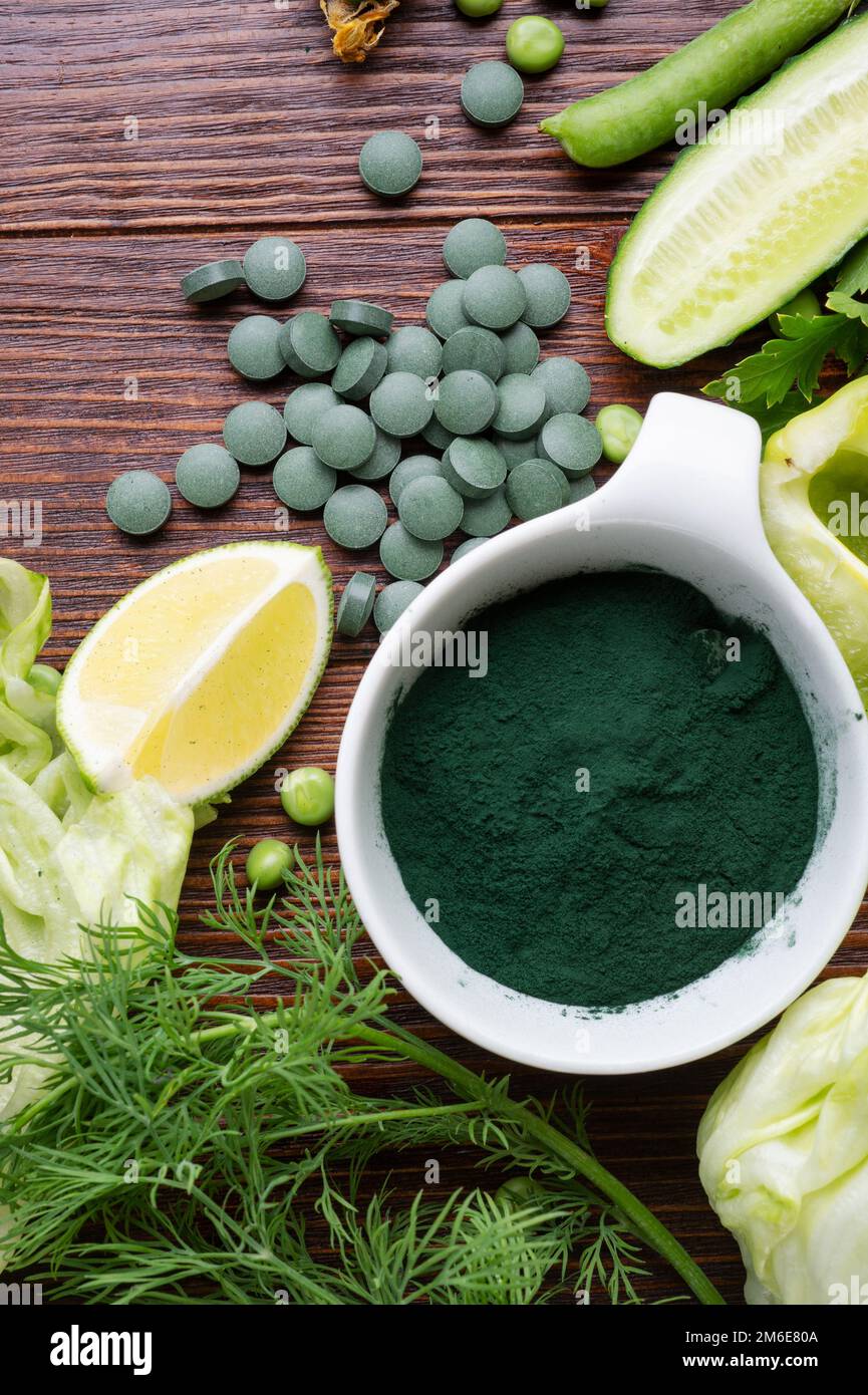 Spirulina-Pulver um grünes frisches Gemüse. Serviert im Woodentable Stockfoto