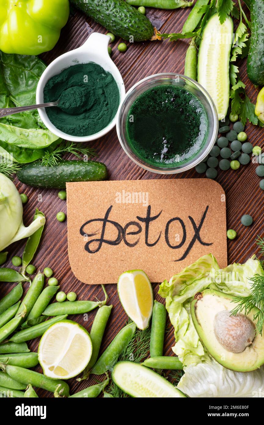 Entgiftungsgrüner Cocktail mit Spirulina um Gemüse. Lifestyle-Konzept. Verschiedene frische grüne Gemüsesorten am Holztisch. Stockfoto