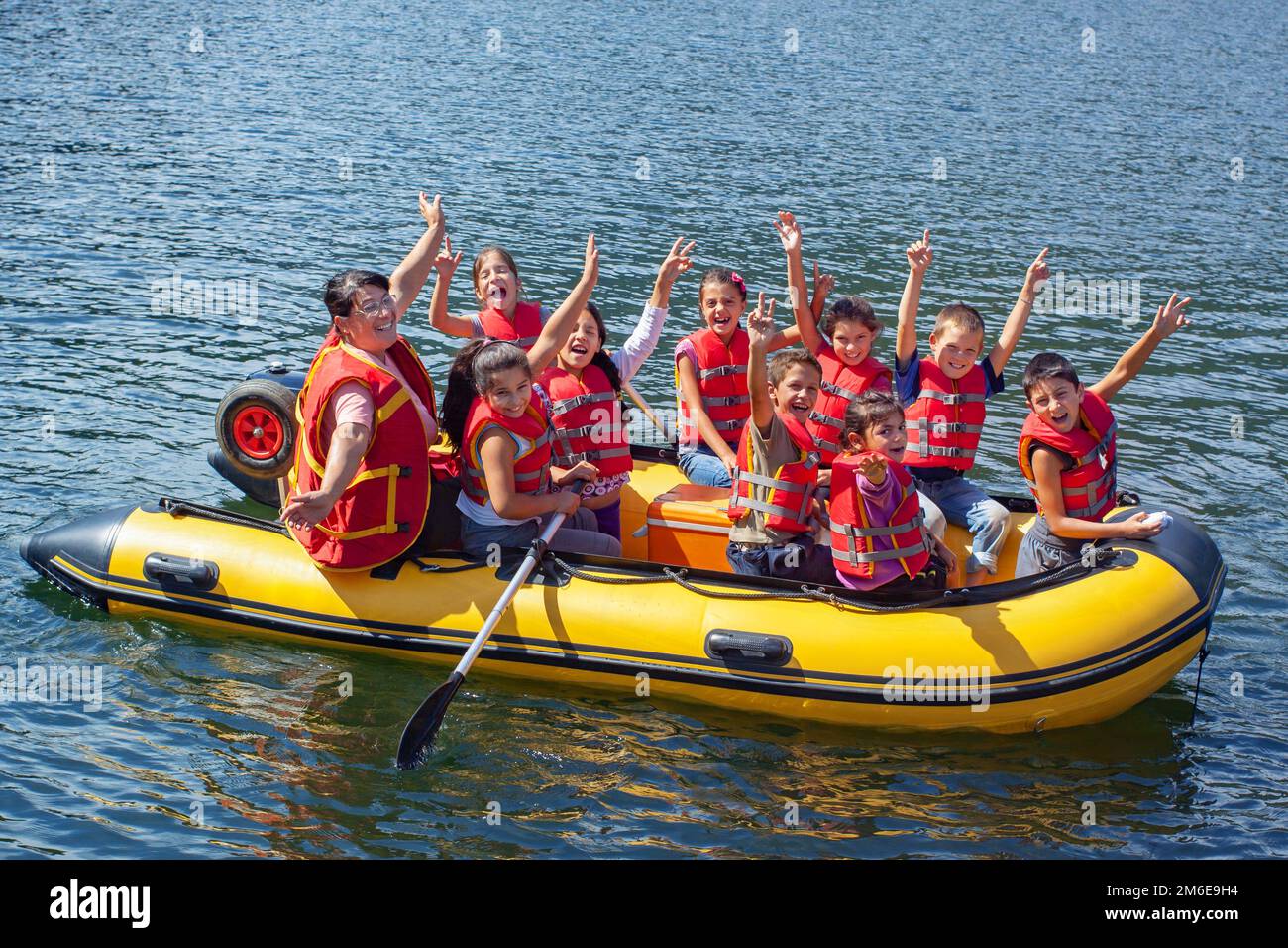 Glückliche Kinder in einem Boot auf dem See, die winken Stockfoto