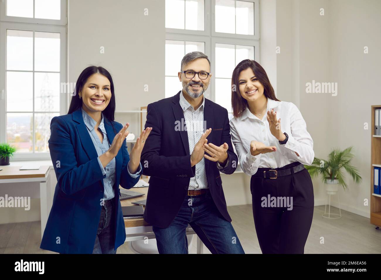 Glückliche Geschäftsleute stehen in einem modernen Büro und applaudieren Stockfoto