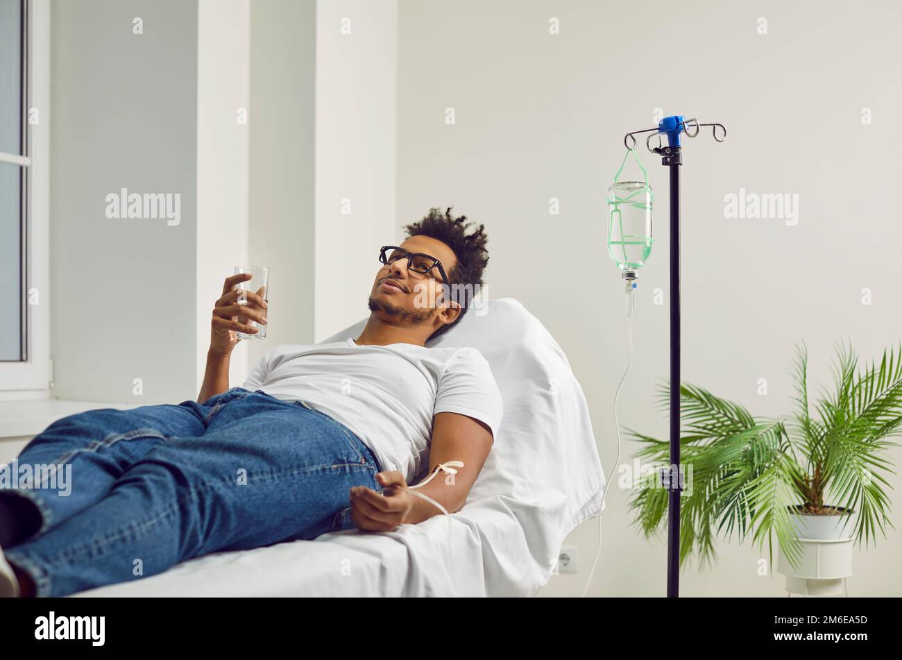 Ein Mann, der Medikamente einnimmt, während er eine intravenöse Tropfinfusion im Krankenhaus erhält Stockfoto