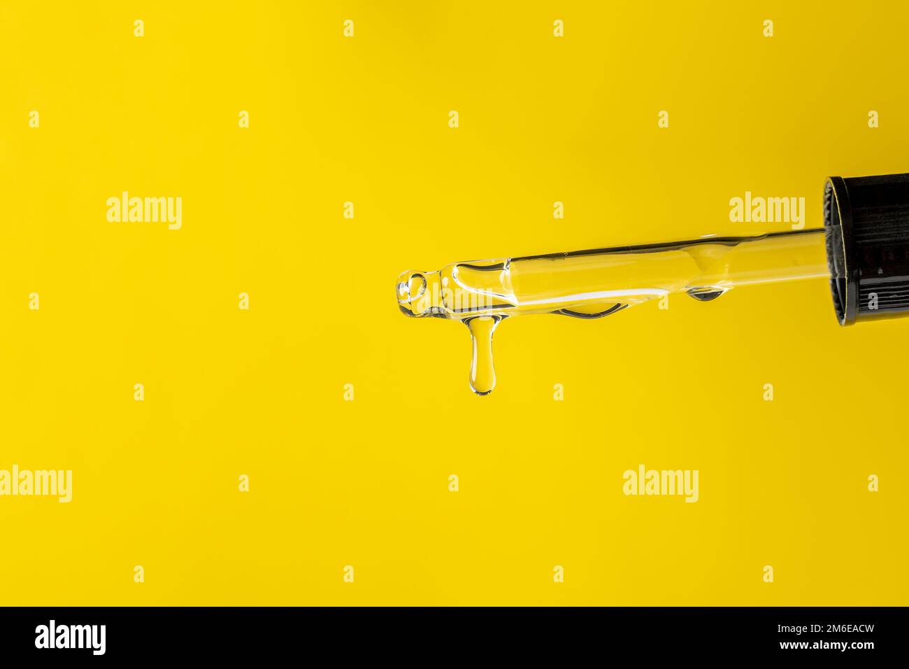 Pipette mit flüssig transparentem Gel, Serum oder ätherischem Öl auf Gelb Stockfoto