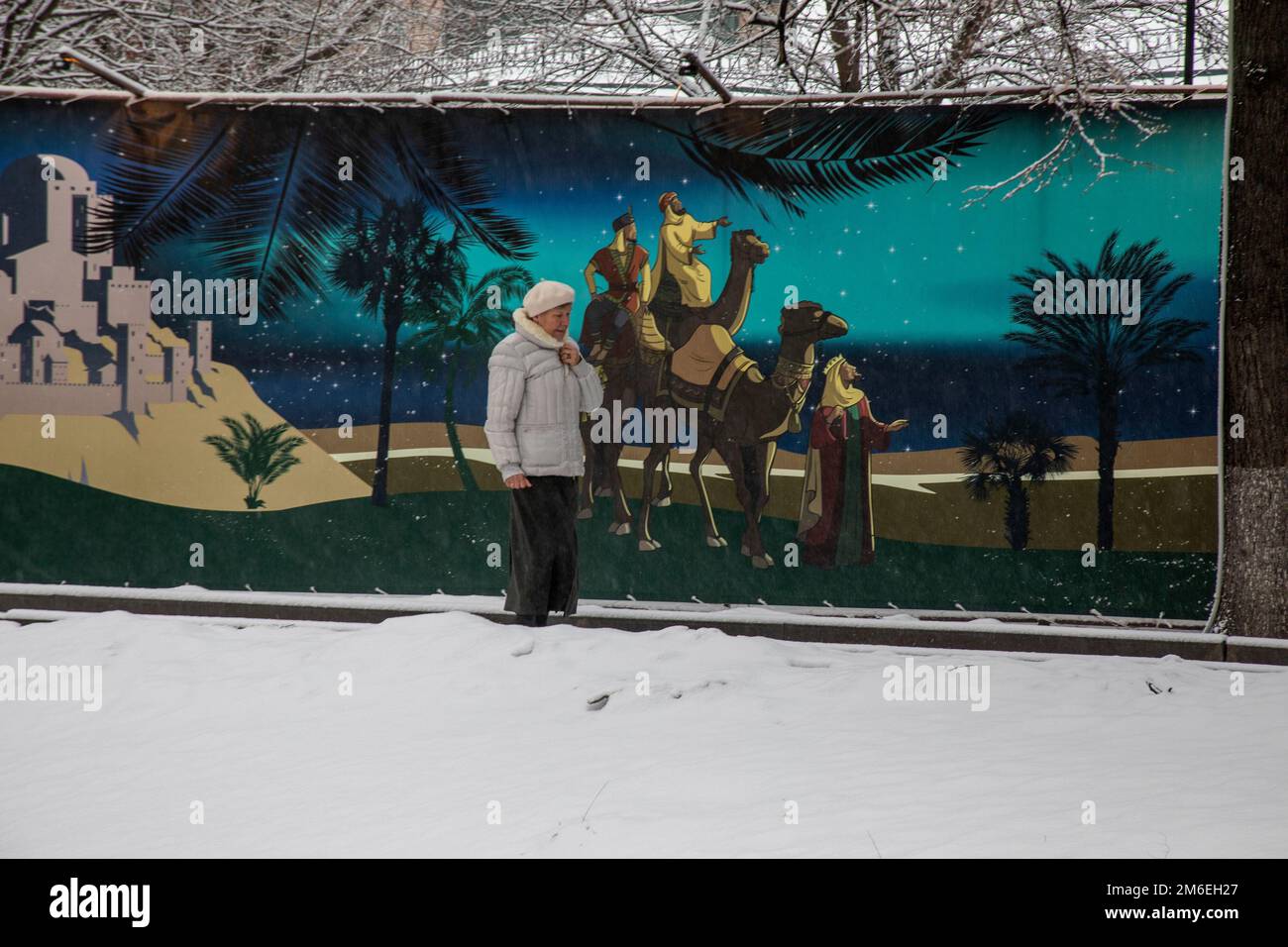 Moskau, Russland. 3. Januar 2023. Eine Frau läuft unter dem Schnee vor einem Wandgemälde, das die biblischen drei Könige (Weisen) im Kloster Vysokopetrovsky im Zentrum von Moskau, Russland, darstellt Stockfoto