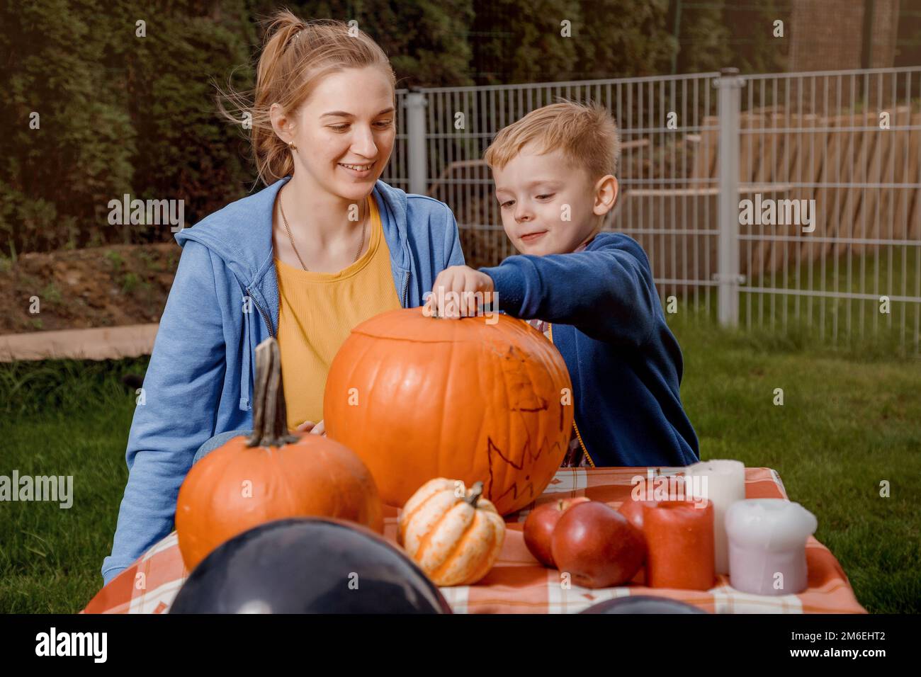 Ein Junge und seine Mutter haben einen Kürbis geschnitten. Eine junge Mutter und ein Sohn bereiten einen Kürbis für Halloween vor. Wir bereiten uns auf Halloween vor. Abziehen Stockfoto