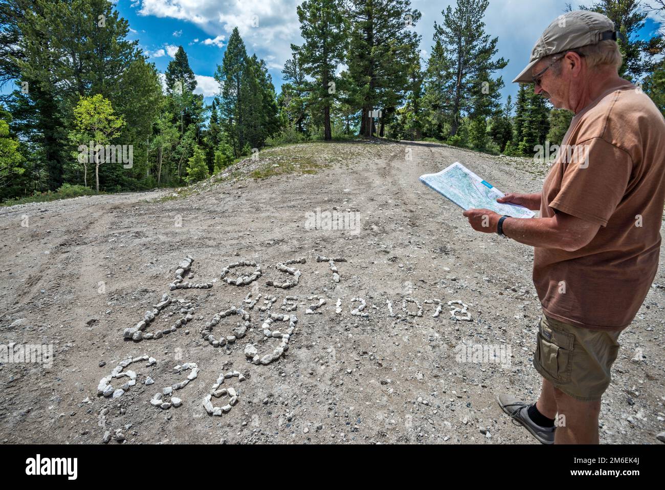Mann überprüft Karte, Schild mit der Schrift „Lost Dog Shingle“ auf der Straßenoberfläche an der Kreuzung von FR 17, FR 143 und FR 140. Escalante Mountains, Utah, USA Stockfoto