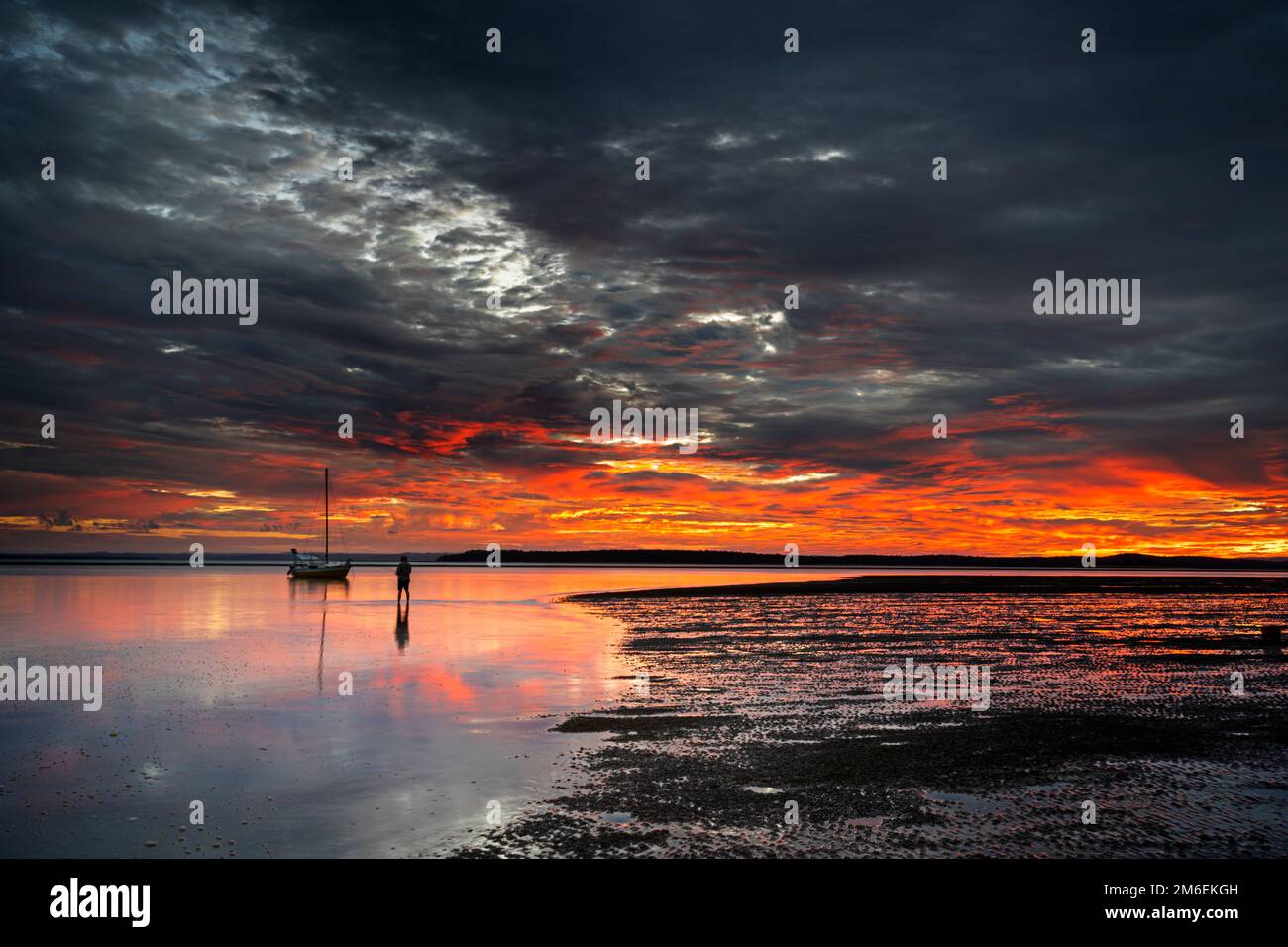 Farbenfroher Sonnenaufgang mit Yacht vor Anker bei Ebbe des Urangan Beach, Hervey Bay Queensland Australien Stockfoto