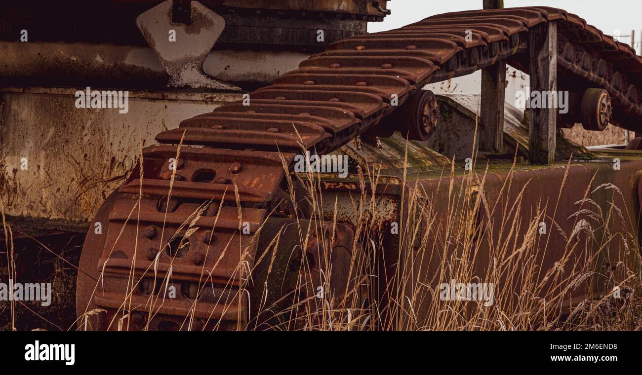 Rusty und Schmutz bedeckt mechanische Caterpillar Track mit Alter Räder und Rollen. Stockfoto