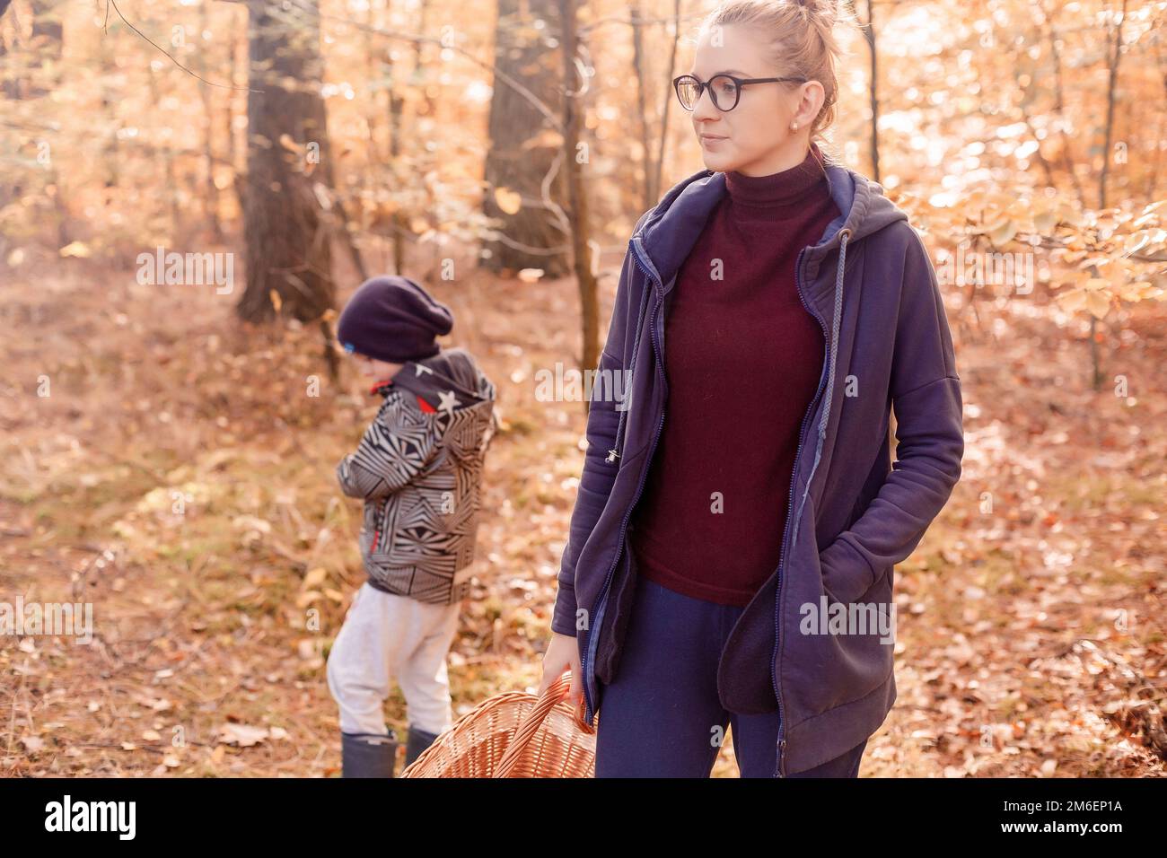 Frau mit Sohn im Herbstwald auf einem Spaziergang. Mädchen im Wald. Stockfoto