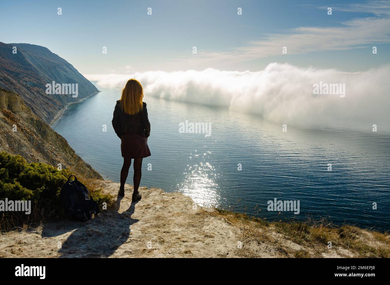 Ein Mädchen steht auf einem Hügel und beobachtet eine ungewöhnliche Phänomen der Natur über dem Meer Stockfoto