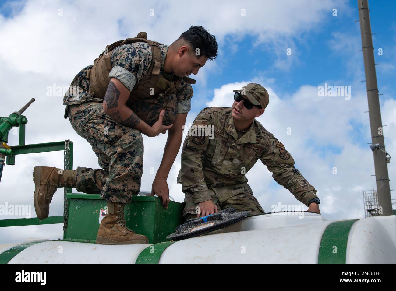 Lance CPL. Fernando Figueroa, Left, Marine Wing Support Squadron 172 Heavy Equipment Mechanic, und Airman 1. Class Gabriel Barba, Right, 18. Civil Engineer Squadron Pavement and Equipment Operator, inspizieren Sie eine 18. CES Hydroseeder in Camp Futenma, Japan, 26. April 2022. Der Hydroseeder wurde für die Renovierung einer Rennstrecke verwendet und bot gleichzeitig eine Schulung für die betroffenen Flugzeuge und Marines an. Stockfoto