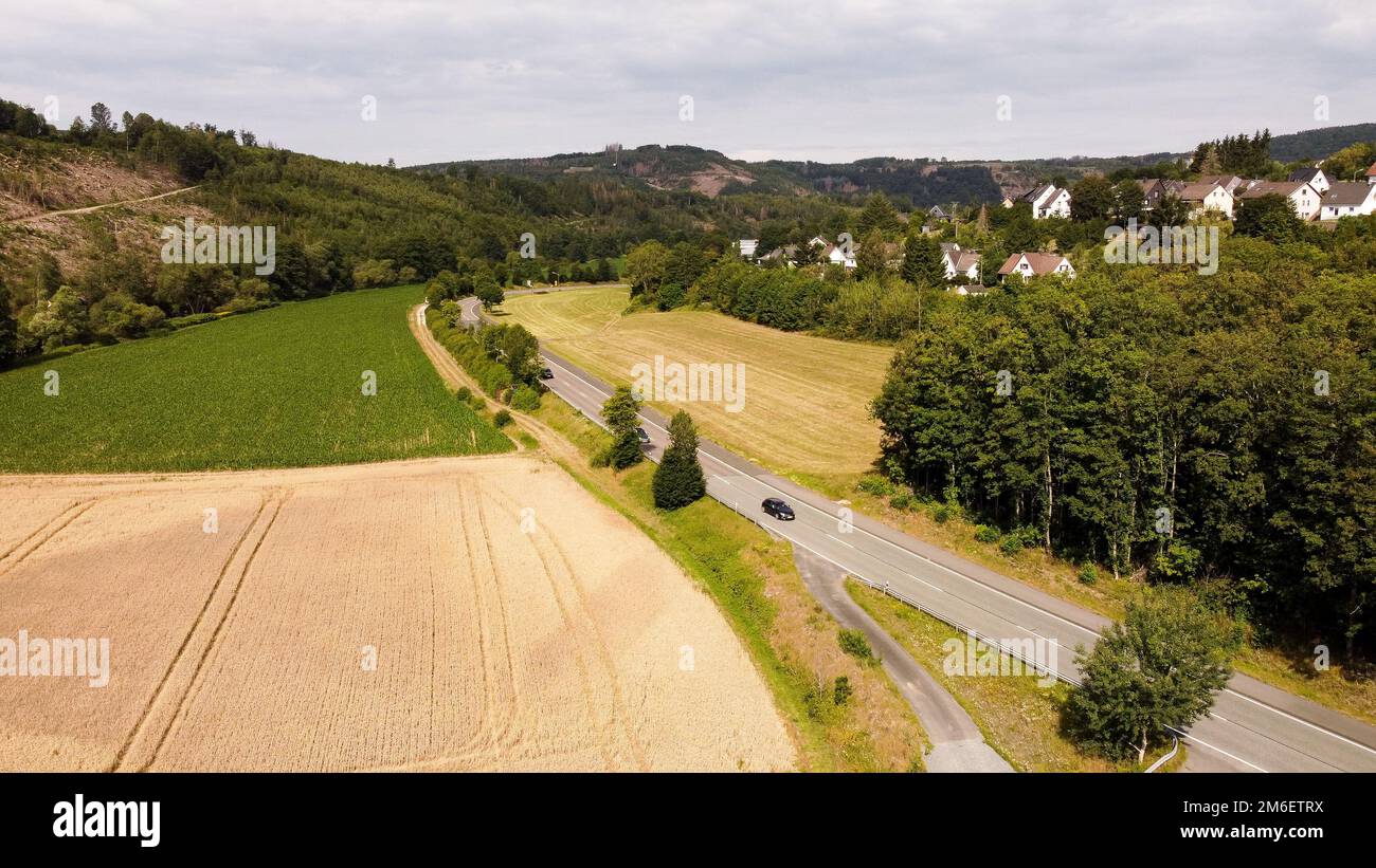 Ländliche Straße in der Nähe eines kleinen Dorfes mit Auto - Drohne oder Luftaufnahme Stockfoto