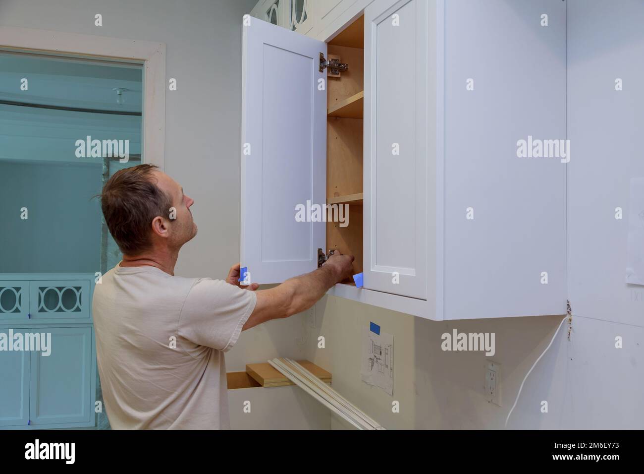 Arbeiter, der an der Tür eines neuen Küchenschranks im neuen Haus arbeitet Stockfoto