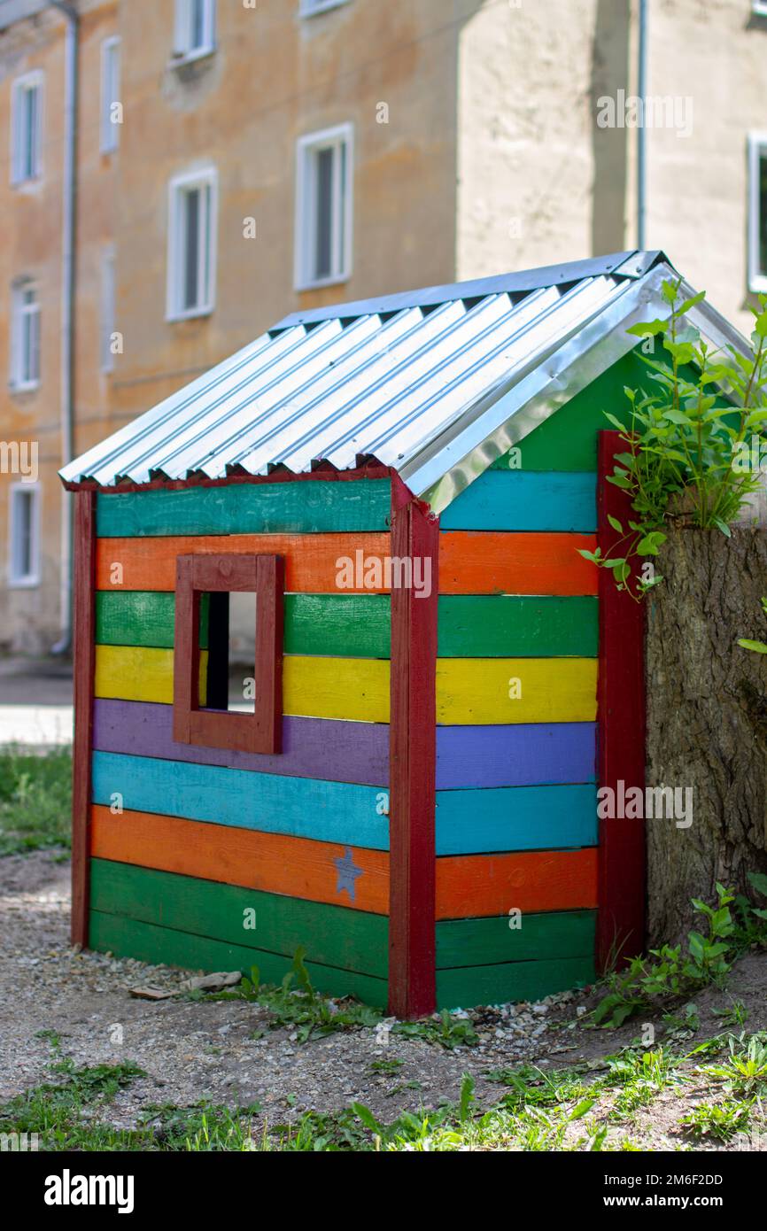 Kinder mehrfarbige hölzerne Haus mit dreieckigem Dach steht auf einem leeren Spielplatz während des Virus und Quarantäne Epidem Stockfoto