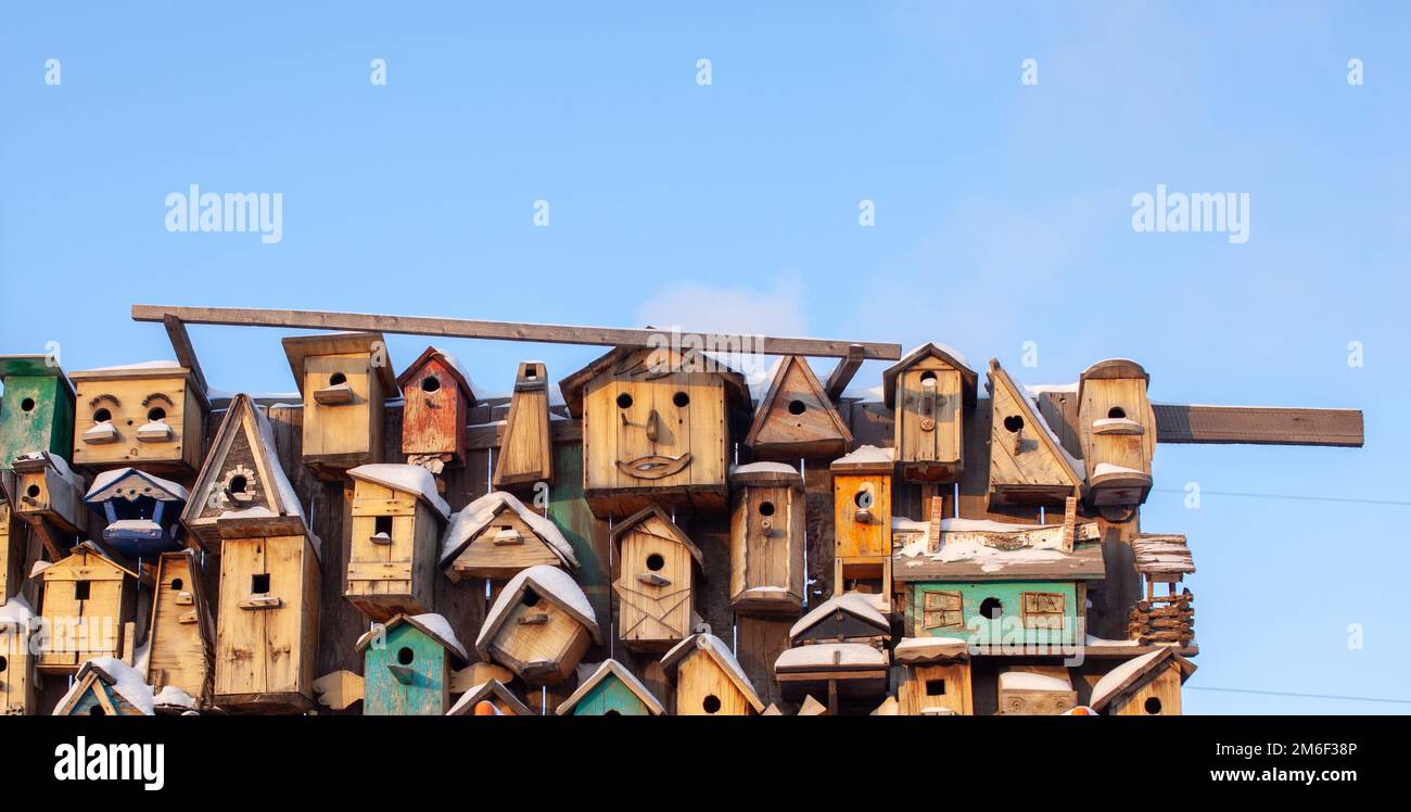 Viele verschiedene Formen von Vogelfutterhäuschen.Vogelhäuser hängen auf einem hölzernen Zaun Stockfoto