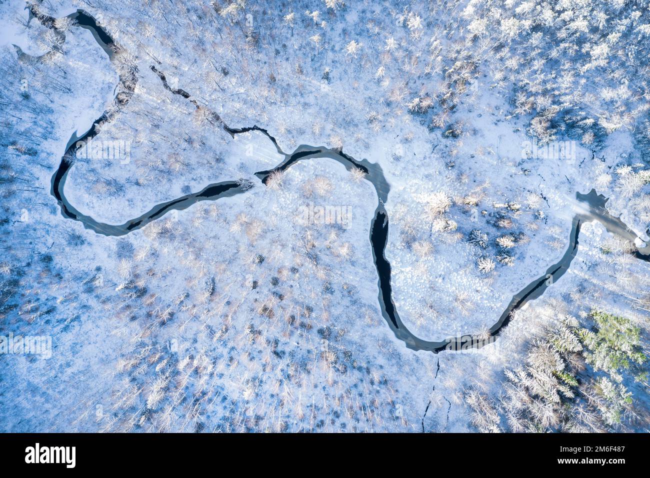 Fluss im Winterwald bei Sonnenuntergang Stockfoto
