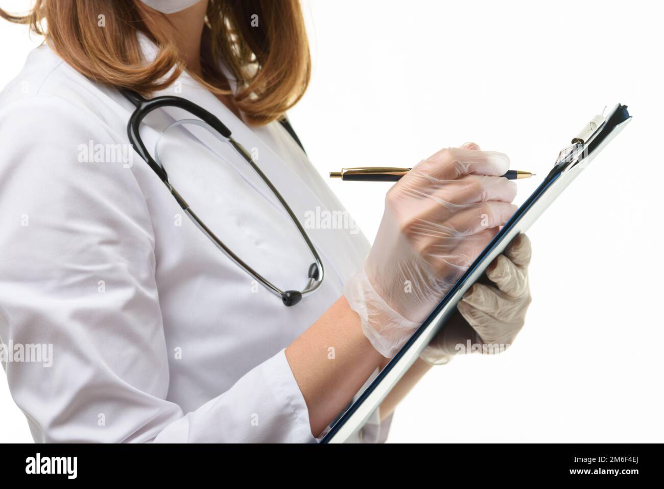 Hände eines Arztes in Handschuhen schreibt mit einem Kugelschreiber in eine Tablette, Nahaufnahme Stockfoto